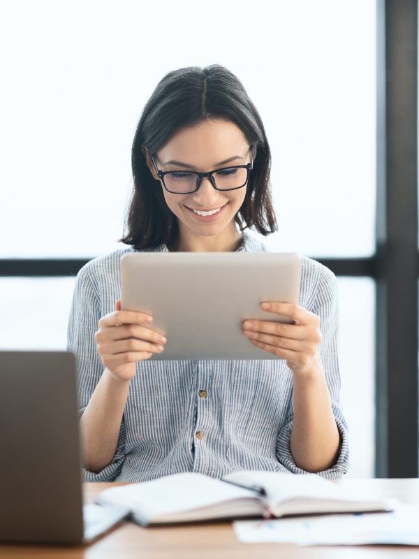 young-girl-holding-tablet-and-using-laptop-at-office.jpg